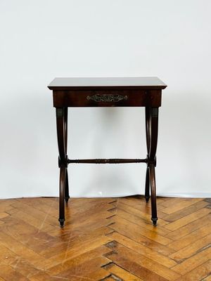 une petite table avec un tiroir, posée sur un parquet