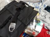 a black bag sitting on top of a bed next to a cell phone