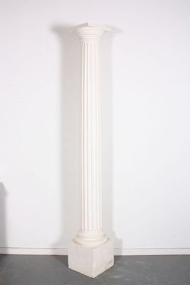 a tall white column with a black base in a room