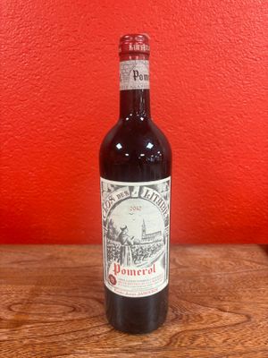 an old bottle of wine sitting on a table in front of a red wall