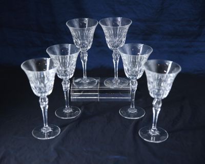 six verres à vin posés sur un présentoir posé sur une table