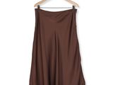 dark brown skirt hanging on a hanger against a white wall