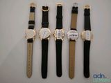 four watches are lined up in a row on a table