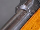 close up of a gun with a wooden handle on a gray background