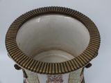 a white vase with a gold rim on a table