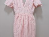 a pink dress hanging on a hanger against a wall