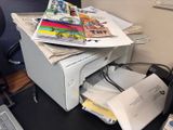 a printer sitting on top of a pile of papers on a desk