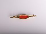 a close up of a gold and red broocher on a white surface