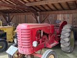 un tracteur rouge garé dans une grange avec d'autres tracteurs