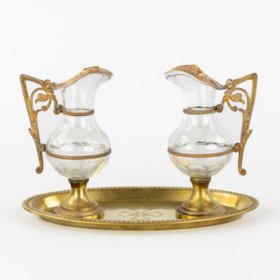 une paire de cruches anciennes en verre et plaquées or, posées sur un plateau