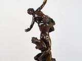 une image représentant une statue en bronze d'un homme assis sur un rocher