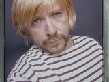 une photo d'un homme aux cheveux blonds portant une chemise rayée