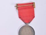 a small medal with a red ribbon on a white background