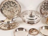 a lot of silver plates and bowls on the table