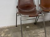 two brown chairs sitting next to each other against a white wall