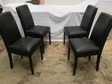 quatre chaises en cuir noir dans une pièce où se trouve une table blanche