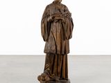 a wooden statue of a man holding a dog in his arms