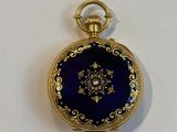 a gold and blue pocket watch on a white surface