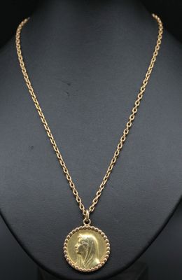 un collier en or avec une pièce de monnaie sur le cou d'un mannequin