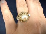 an image of a woman ' s hand with a pearl and diamond ring