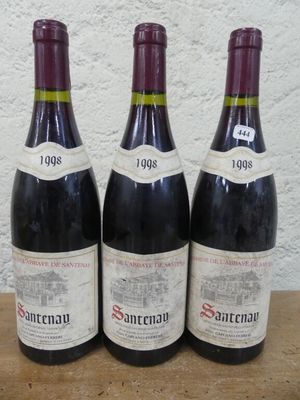 trois bouteilles de vin sont alignées sur une table en bois