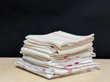 une pile de cinq nappes blanches et rouges posée sur une table en bois