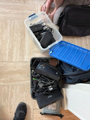 a person sitting on the floor next to a suitcase full of electronics