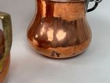 two copper pots sitting next to each other on a table