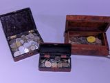 trois petites boîtes en bois contenant des pièces de monnaie, posées sur une surface blanche