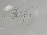 a signé des autographes sur un tableau blanc dans la vitrine d'un magasin