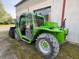 a green tractor parked in front of a building