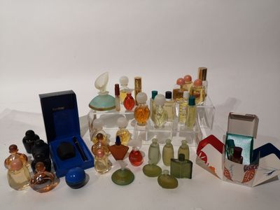 de nombreux flacons de parfum posés sur une surface blanche