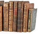 several old books are stacked on top of each other on a white surface