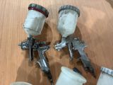 three spray guns and a cup of paint on a table