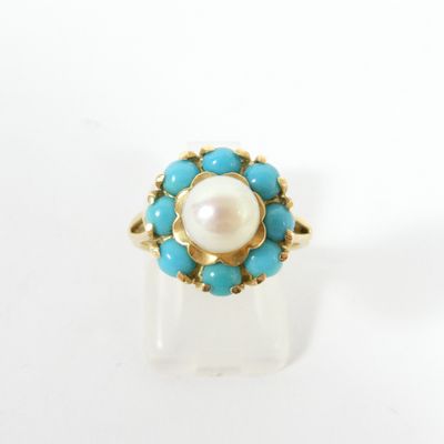 un gros plan d'une bague ornée d'une perle et de perles de turquoise