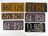 cinq plaques d'immatriculation différentes exposées sur une surface blanche