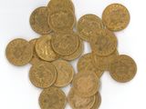 quelques pièces d'or posées sur une surface blanche, sur fond blanc