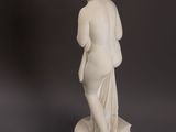 statue of a woman standing on a pedestal on a gray background