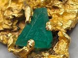 gold nugget with a piece of green stone on top of it