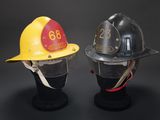 two firemen helmets on display on a black background