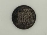 an old silver coin with a statue on it on a white surface