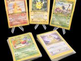 Quatre cartes Pokémon sont exposées sur une surface noire.