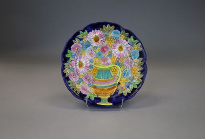 a blue and yellow plate with a vase of flowers on it