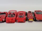 five red cars lined up in a row on a white surface