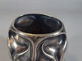 a silver vase with a face on it sitting on a table