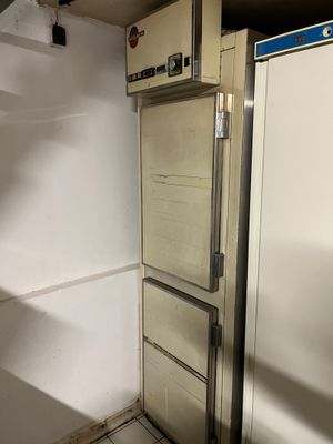 a refrigerator in the corner of a room with a door open