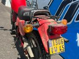 une moto rouge garée devant un bus bleu et blanc