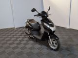 un scooter noir garé dans une pièce au sol en damier