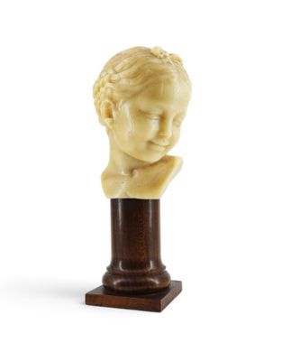 a close up of a sculpture of a child ' s head on a wooden base