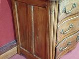 a wooden chest of drawers in a room with a pink wall
